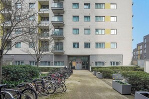 Un edificio residencial de varios pisos con una zona de estacionamiento para bicicletas al frente.