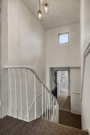 Eine Treppe mit weißen Balustraden, die zu einer Zwischenebene im zweiten Stock führt.