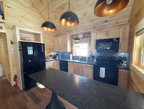 Eine moderne Küche mit Holzausbau, einem schwarzen Kühlschrank, einer Mikrowelle und einer großen Arbeitsfläche.