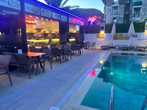Zona junto a la piscina con bar y asientos.