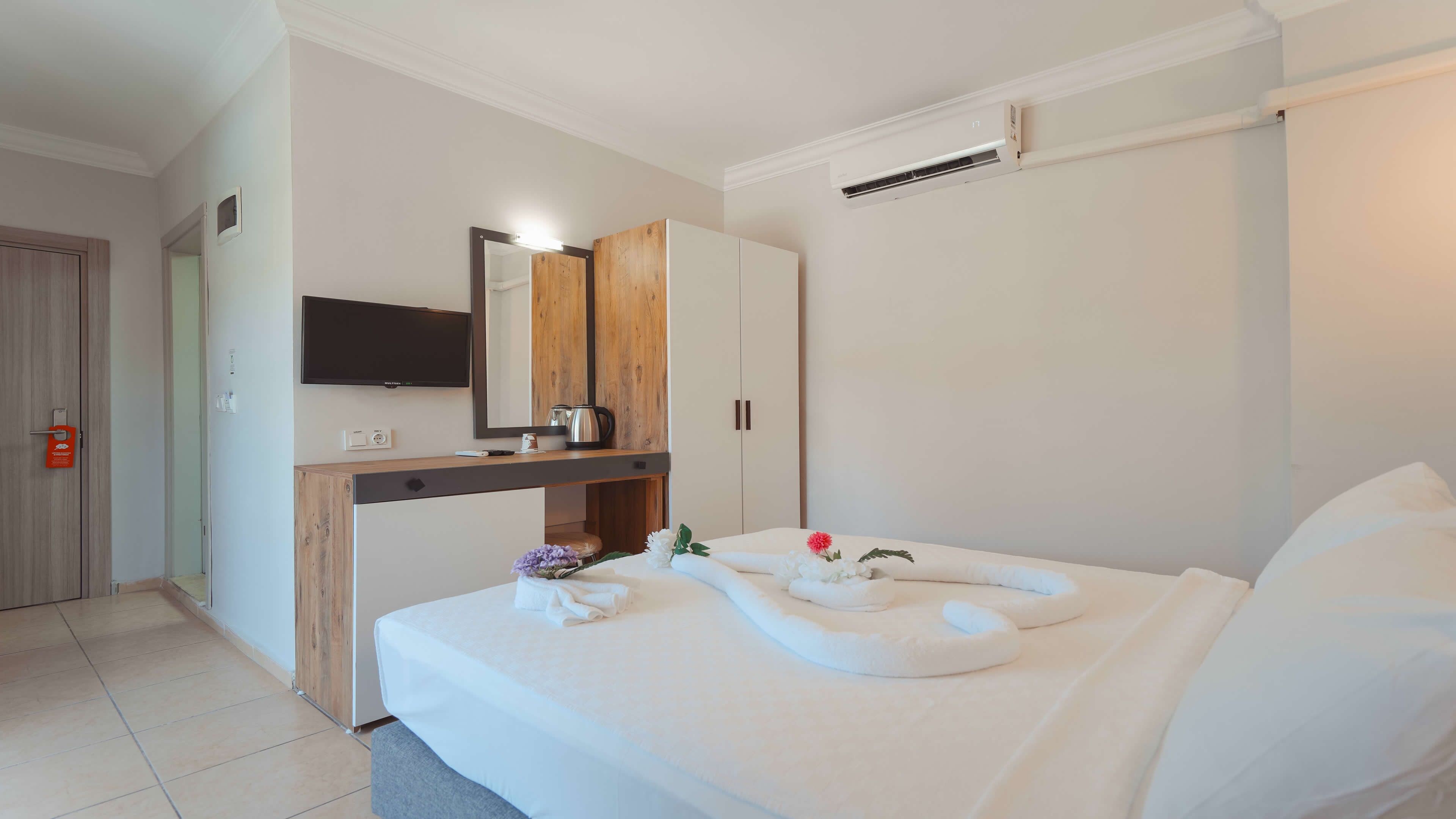 Una habitación de hotel con cama, escritorio con espejo, televisor y armario.