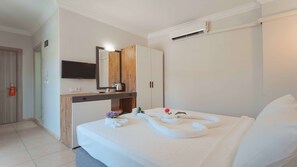 Una habitación de hotel con cama, escritorio con espejo, televisor y armario.