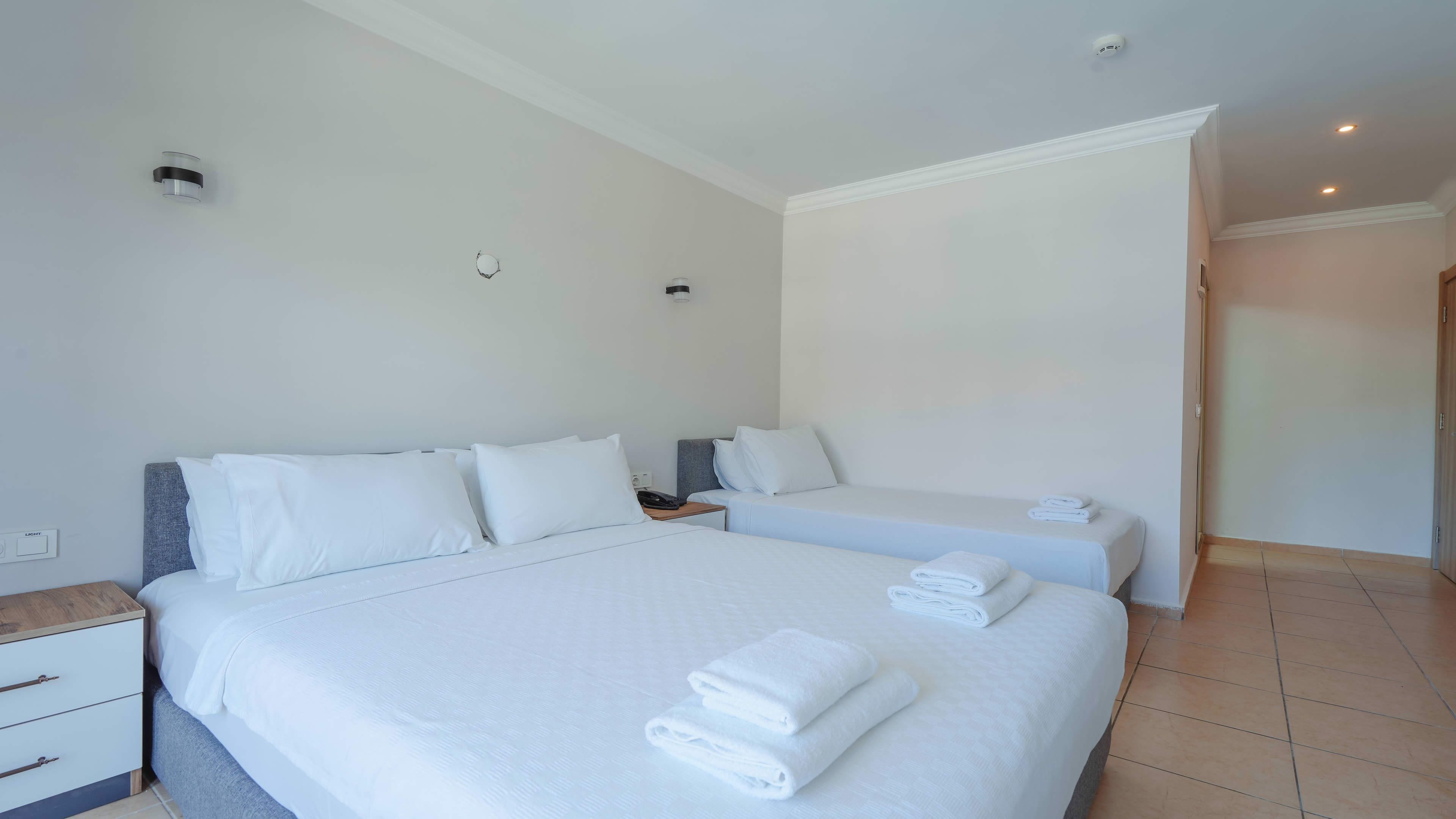 Quarto de hotel com duas camas, mesa de cabeceira, abajur e porta.