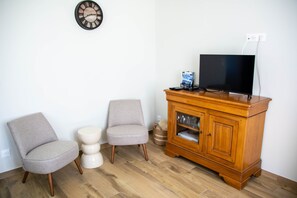 A room with a wooden cabinet, a television, and two chairs. - Holiday Home 'La Parenthèse Cauchoise' with Sea View, Comfort and Tranquility (Malleville-les-Grès)