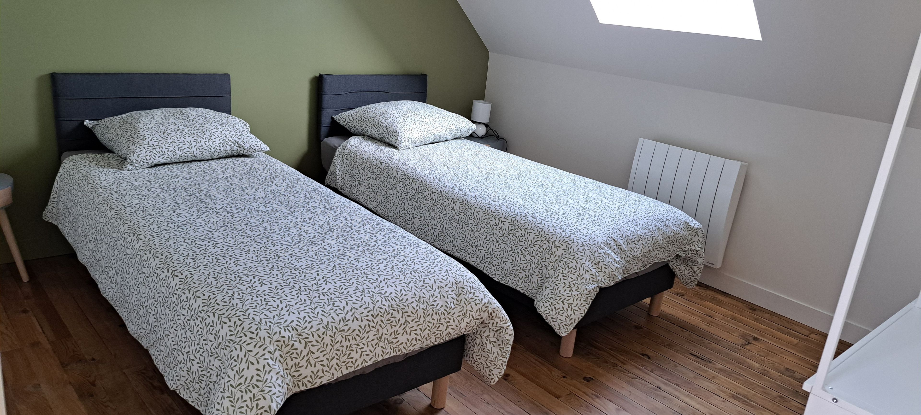 Une chambre avec deux lits, une table de chevet, une lampe et un radiateur.