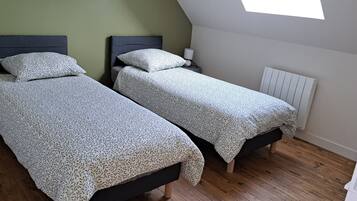 Una habitación con dos camas, una mesita de noche, una lámpara y un radiador.