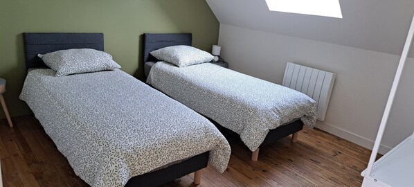 A room with two beds, a nightstand, a lamp, and a radiator. - Holiday Home 'La Parenthèse Cauchoise' with Sea View, Comfort and Tranquility (Malleville-les-Grès)