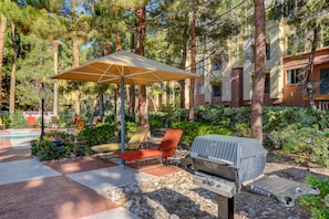 Eine Außenpatio-Terrasse mit Grill, Liegestühlen und einer überdachten Sitzgelegenheit.