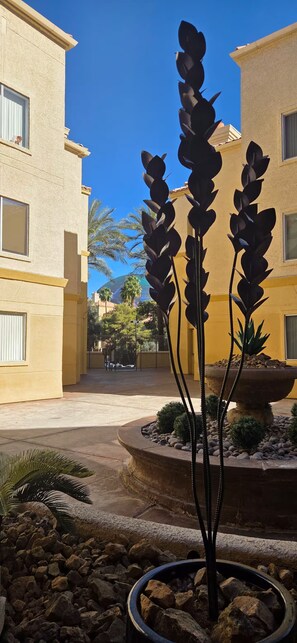 A courtyard with a central sculpture, buildings with balconies, and a clear blue sky. - Luxury Las Vegas Strip!  1BR Private Residences Condo ~ 24/7 Pool 2-09 (Las Vegas)