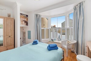 Ein Schlafzimmer mit Bett, Schreibtisch, Stuhl und Blick ins Freie.
