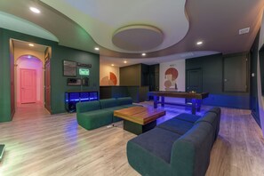 Een moderne lounge met een pooltafel, banken en een bar voorzien van neonreclame.