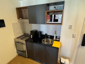 A compact kitchenette with a gas stove, coffee maker, microwave, and a small sink. - Hermo Studio, 2 meters from the MOVISTAR ARENA - Palermo Queens (Buenos Aires)