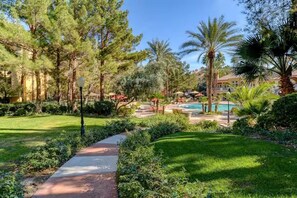 Un complexe hôtelier doté d’une piscine, de palmiers et d’une pelouse bien entretenue.