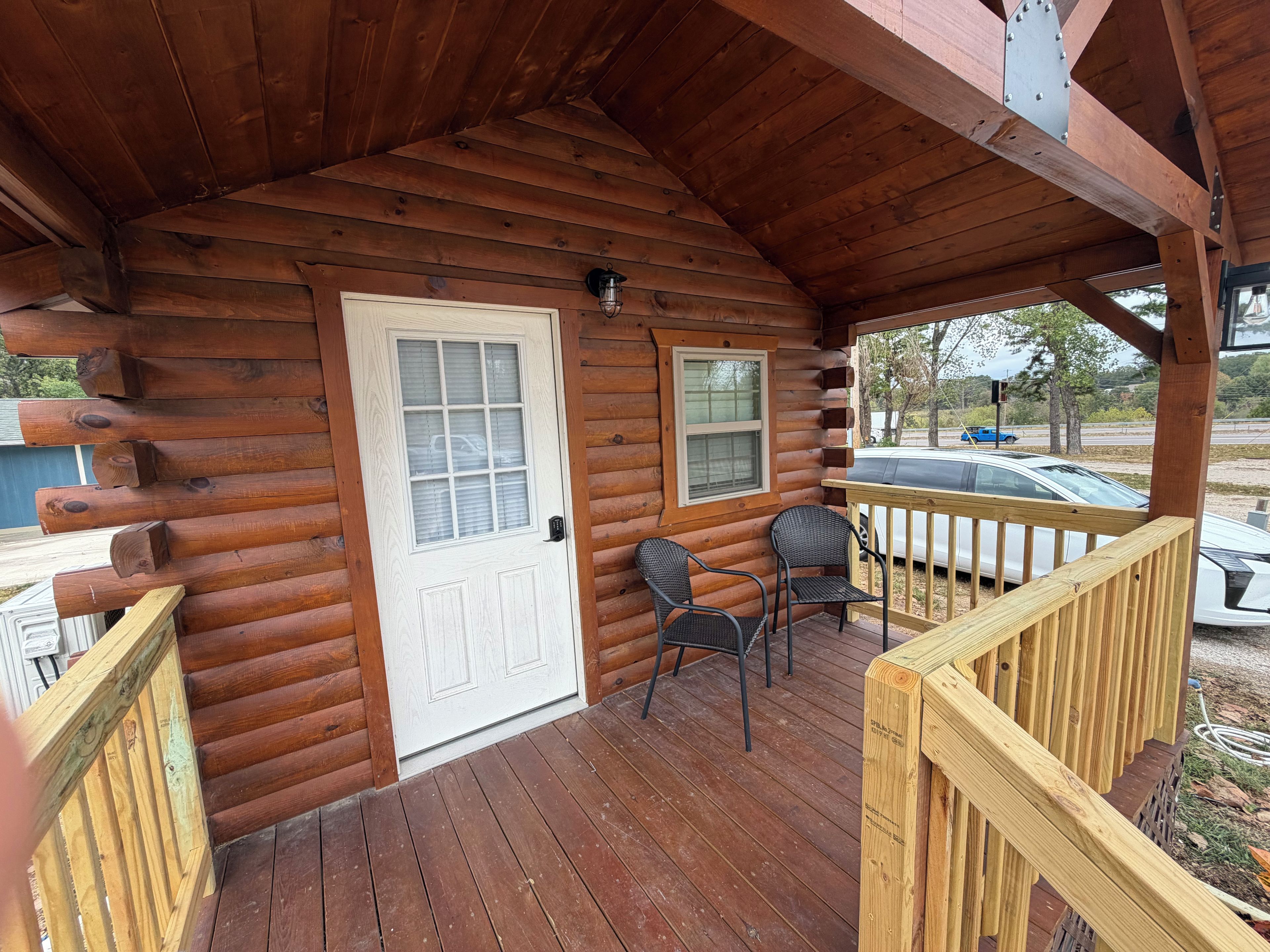 A log cabin with a porch, a door, and two windows.