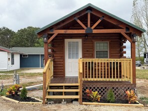 A small log cabin with a front porch, a door, and windows.
