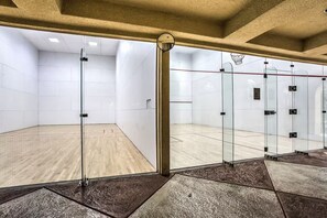 Ein Squashplatz mit Glaswänden, Holzboden und einer Decke mit eingelassener Beleuchtung.
