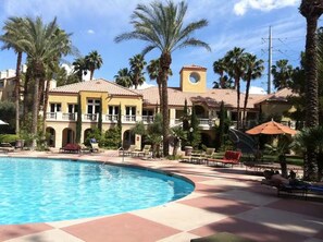 A resort with a swimming pool, palm trees, and a building with a tower. - Luxury Las Vegas Strip!  1BR Private Residences Condo ~ 24/7 Pool 2-22 (Las Vegas)