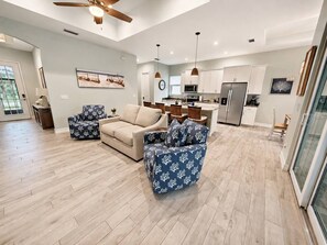 A spacious living area with a sofa, armchairs, and a dining area with a kitchen in the background. - Heated Saltwater Pool | Near Beach | Pets Welcome! (Rotonda West)
