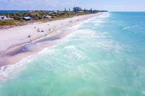 A beach with clear turquoise water, a sandy shore, and a few buildings in the background. - Heated Saltwater Pool | Near Beach | Pets Welcome! (Rotonda West)