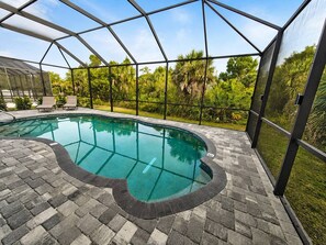 A swimming pool with a brick deck, surrounded by a glass enclosure with a metal frame. - Heated Saltwater Pool | Near Beach | Pets Welcome! (Rotonda West)