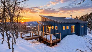 A cabin with a wooden deck and a view of the sunset.
