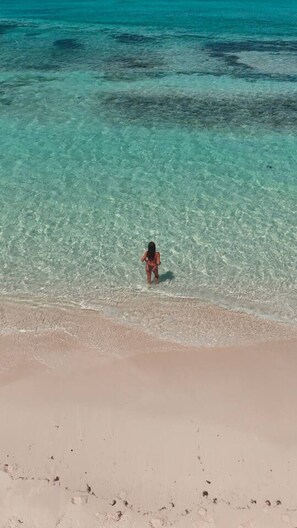 Ein Strand mit klarem, flachem Wasser und einer Person, die darin steht.