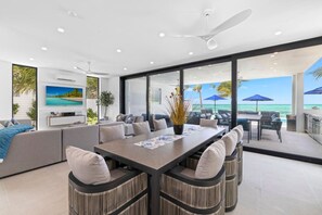 Ein modernes Interieur mit Essbereich, Sofas und Blick auf den Ozean.