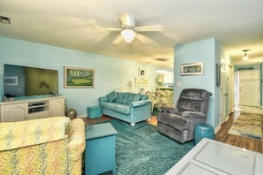 A living room with a television, a sofa, a chair, and a ceiling fan. - Sea Horse Beach House 2BR 3BA Sleep7,with Pool Near Cherry Grove4Mile From Beach (Little River)