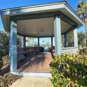 A covered pavilion with a wooden deck, benches, and a lattice railing. - Sea Horse Beach House 2BR 3BA Sleep7,with Pool Near Cherry Grove4Mile From Beach (Little River)