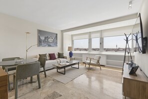 Sala de estar moderna com área de jantar, janelas amplas e vista para a cidade.