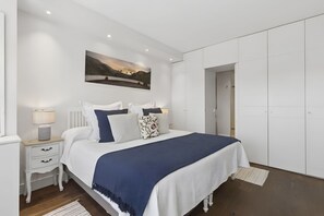 A bedroom with a bed, bedside tables, a lamp, a painting, and a wardrobe. - Elegant 1BR in Prime Colón Madrid (Madrid)