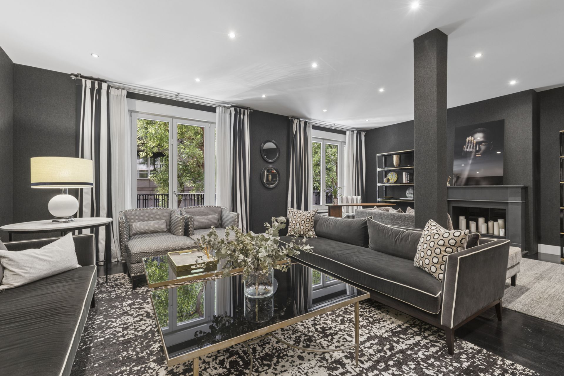 A modern living room with a sofa, armchairs, a coffee table, and a fireplace.
