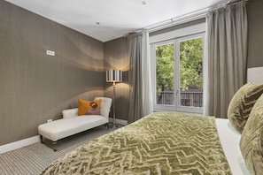Ein Hotelzimmer mit einem Bett, einer Bank, einer Stehlampe und Blick auf Grünfläche.