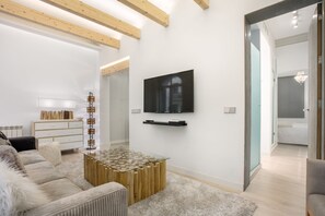 A modern living room with a glass coffee table, a flat-screen TV, and a wooden beam ceiling. - Stylish Stay in Salamanca (Madrid)