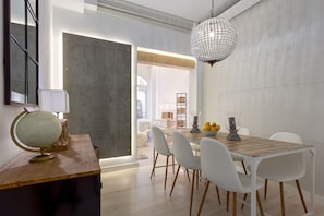 A dining area with a wooden table, white chairs, and a globe on a wooden stand. - Stylish Stay in Salamanca (Madrid)