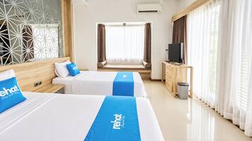 A hotel room with two beds, a TV, and a window with curtains.