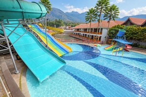 A swimming pool with multiple slides and a view of a mountainous landscape.