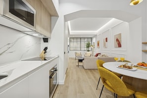 Eine moderne Küche mit Backofen, ein Essbereich mit gelben Stühlen und ein großes Fenster.