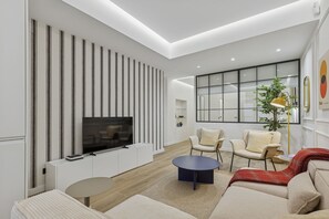 A modern living room with a flat-screen TV, two sofas, a coffee table, and a large window. - Spacious Home in the Heart of Chamberí (Madrid)