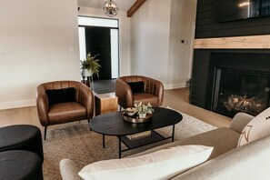 Ein Wohnzimmer mit Ledersesseln, einer Couch, einem Couchtisch und einem Kamin.
