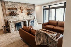 Ein modernes Wohnzimmer mit Kamin aus Stein, einer Ledersofa und einem großen Fenster.