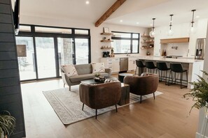 Cuina moderna amb armaris blancs, una illa central i il·luminació penjant.