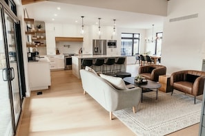 Une cuisine moderne avec des meubles blancs, des appareils en acier inoxydable et un îlot central doté de tabourets de bar.