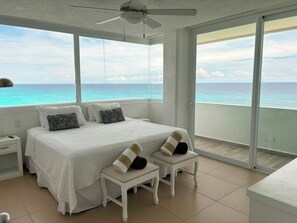 A bedroom with a bed, nightstands, a ceiling fan, and a view of the ocean. - Oceanfront Loft, Hotel District - At Oleo Resort (Cancún)