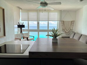 A room with a large window, a ceiling fan, a dining table, and a seating area. - Oceanfront Loft, Hotel District - At Oleo Resort (Cancún)