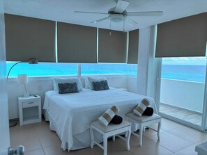 A bedroom with a bed, bedside tables, a lamp, and a view of the ocean. - Oceanfront Loft, Hotel District - At Oleo Resort (Cancún)