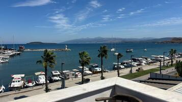 Un puerto deportivo con barcos, un faro y montañas al fondo.