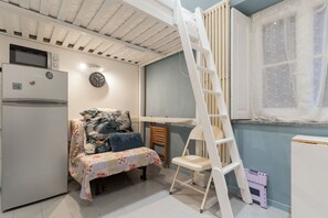 A bedroom with a bunk bed, a desk, a ladder, a refrigerator, and a window with a curtain. - GuestHost - Cozy Apartment in Downtown Milan (Milan)