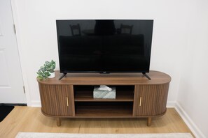 A flat-screen TV on a wooden entertainment center with two cabinets and a small shelf.