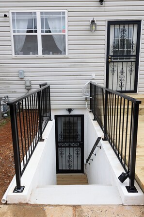 A white building with a black metal staircase leading to a door with intricate designs.